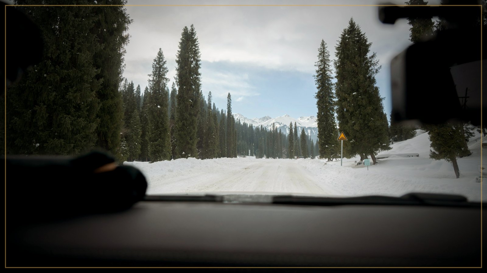 Dash cam view of a snowy forest road